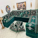 Emerald green Majlis sofa with intricate white embroidery patterns.