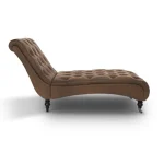 Side view of a brown leather chaise lounge with button tufting and wooden legs.