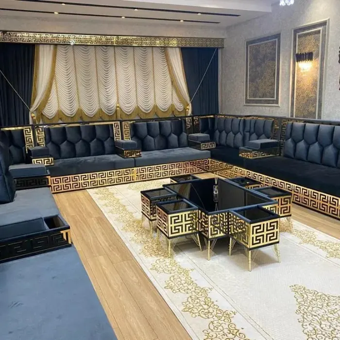 A stylish black and gold majlis sofa featuring plush seating, decorative throw pillows, and a unique coffee table setup.
