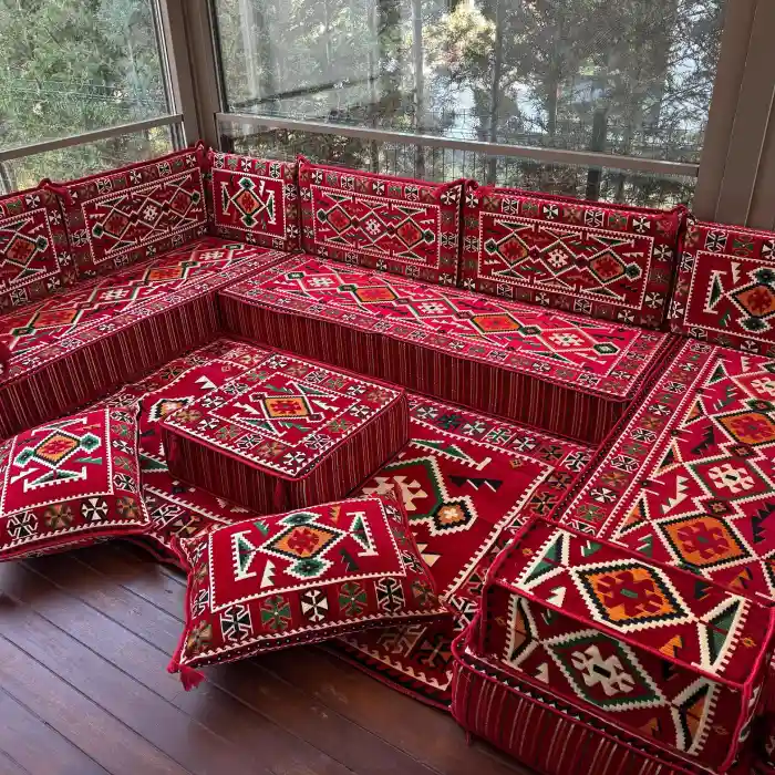 Comfortable Majlis sofa in rich red tones, showcasing cultural design elements in a modern setting with large windows.