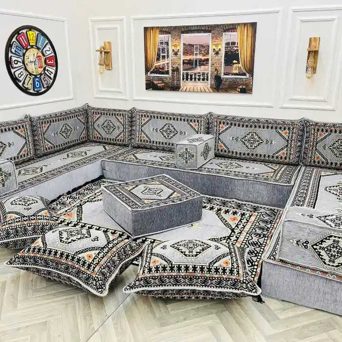 Modern gray modular majlis sofa set with intricate patterns on cushions and a matching rug.